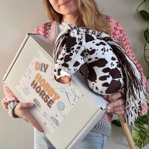May include: A DIY hobby horse kit with a brown and white horse head, a wooden stick, and a white box with the text "DIY Hobby Horse" on it.