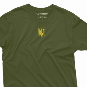 May include: A green t-shirt with the Ukrainian coat of arms printed on the front. The shirt is made of 100% cotton and is available in sizes S-XXL.
