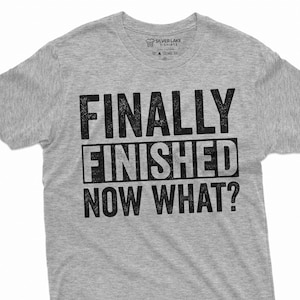 Puede incluir: Camiseta gris con el texto "FINALLY FINISHED NOW WHAT?" impreso en negro.