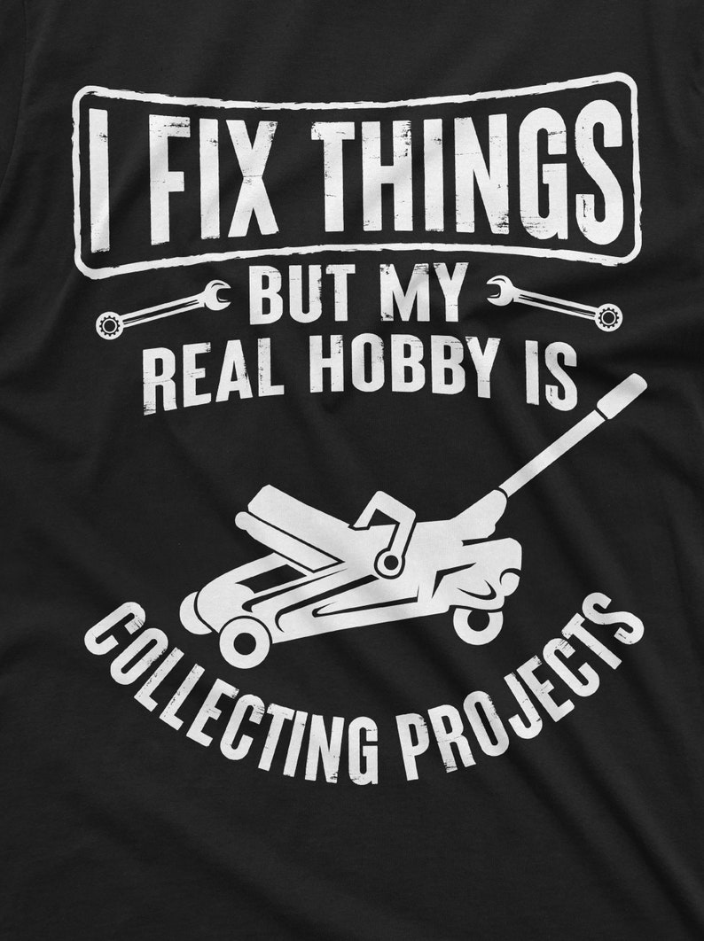 May include: A black t-shirt with white text that reads "I fix things but my real hobby is collecting projects". A white silhouette of a car jack is below the text.