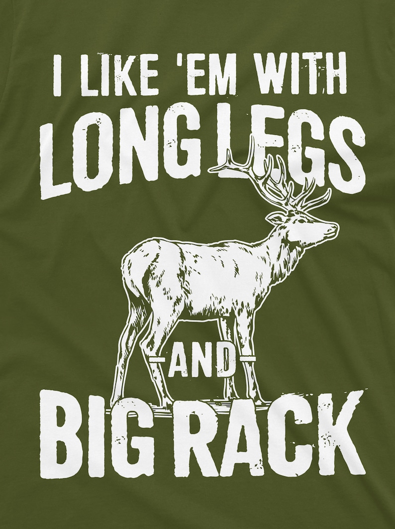 May include: A green t-shirt with white text that reads "I like 'em with long legs and big rack". A white silhouette of a deer with large antlers is in the center of the shirt.