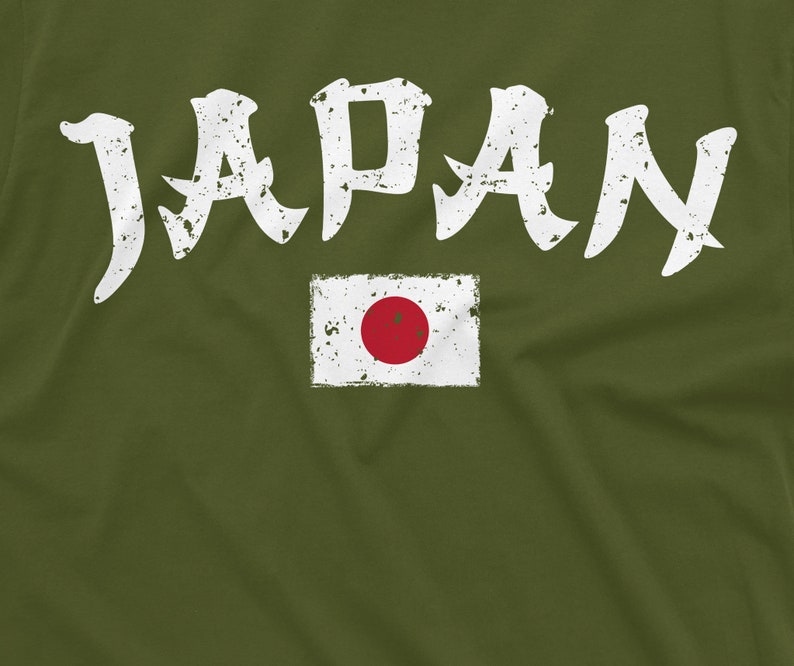 May include: A green t-shirt with the word "JAPAN" in white distressed lettering and a white distressed image of the Japanese flag with a red circle in the center.