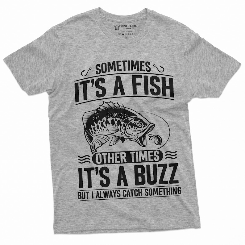 Pu&ograve; includere: T-shirt grigia con una grafica nera di un pesce e il testo "Sometimes it's a fish, other times it's a buzz, but I always catch something."