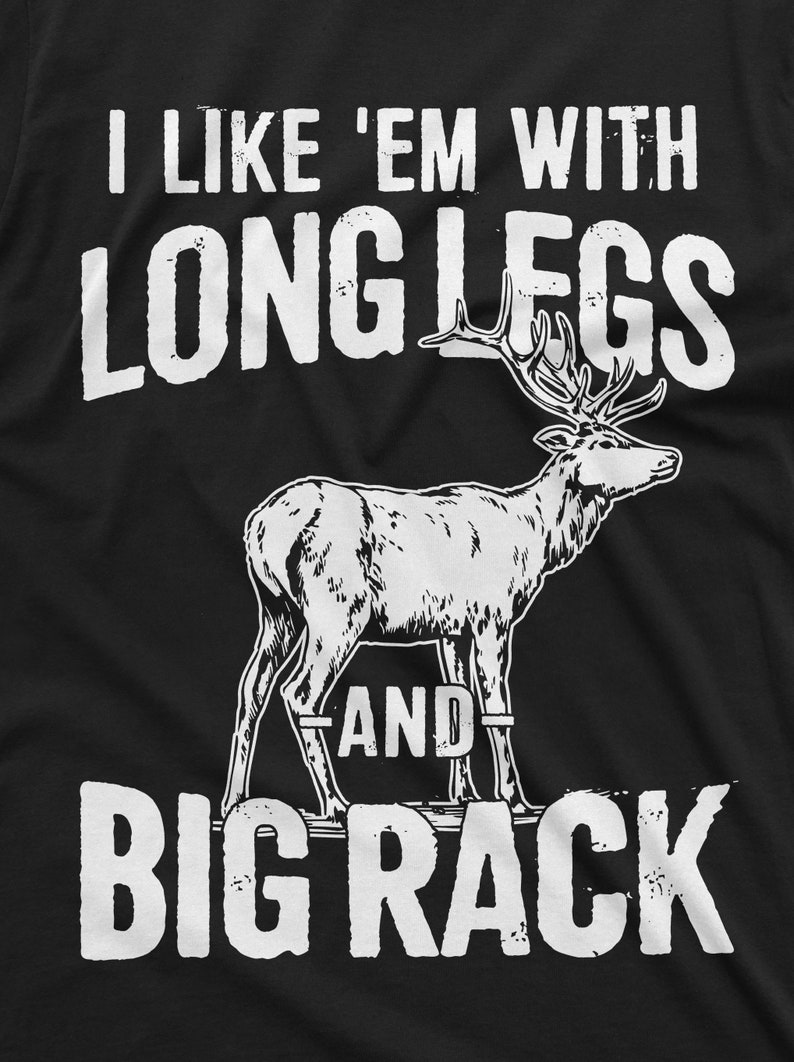 May include: A black t-shirt with white text that reads "I like 'em with long legs and big rack". A white silhouette of a deer with large antlers is in the center of the shirt.
