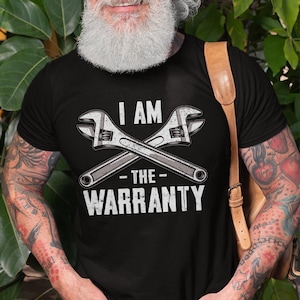 May include: A black t-shirt with a white graphic of two crossed wrenches and the text "I AM THE WARRANTY".