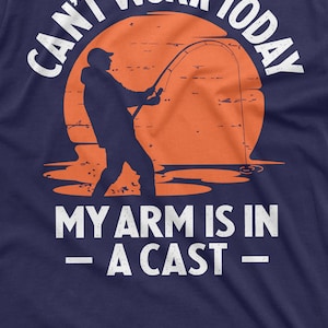 May include: A navy blue t-shirt with a white graphic of a person fishing with the text "Can't work today - my arm is in a cast -"