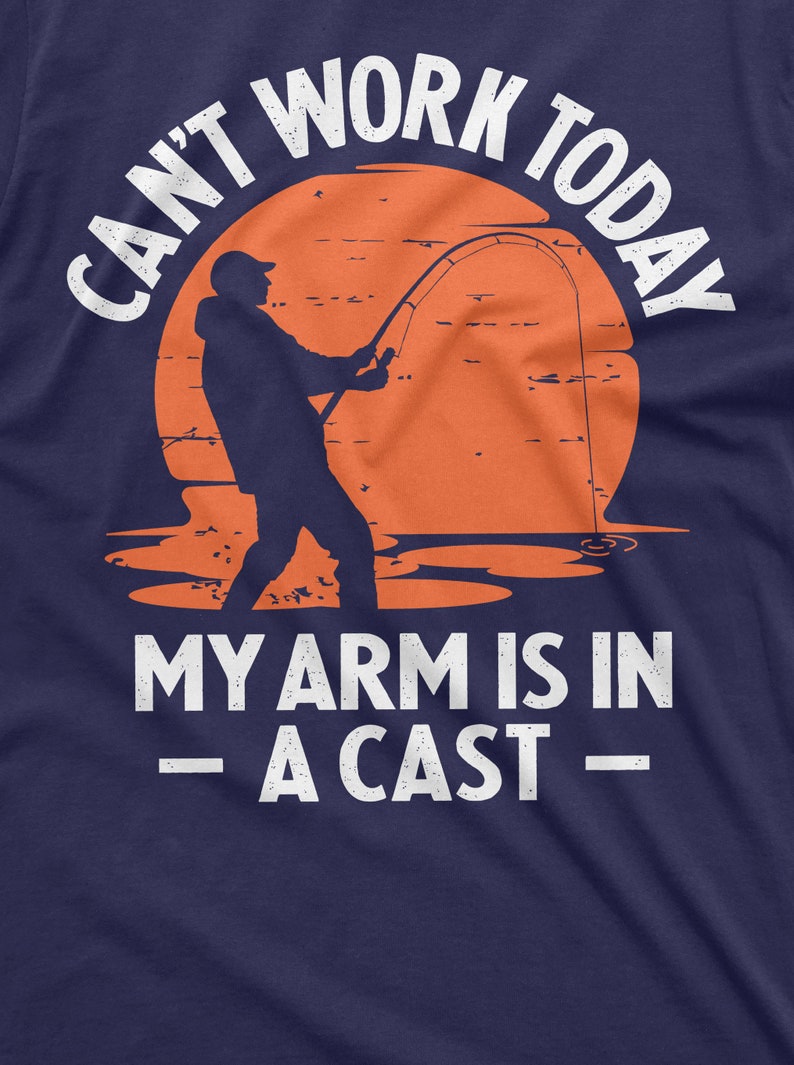 May include: A navy blue t-shirt with a white graphic of a person fishing with the text "Can't work today - my arm is in a cast -"