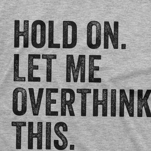 May include: Grey t-shirt with the text "HOLD ON. LET ME OVERTHINK THIS."