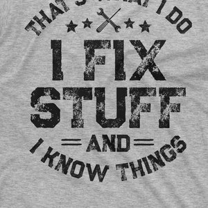 May include: A gray t-shirt with a distressed black graphic that reads "That's what I do I fix stuff = and = I know things". The graphic also includes a wrench and three stars.