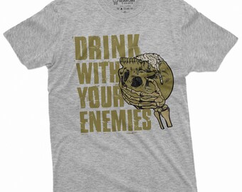 以下が含まれることがあります： くすんだグレーのTシャツに、ビールジョッキを持った骸骨のヴィンテージ調のグラフィックがプリントされています。テキストは「Drink with your enemies」で、ヴィンテージ調のフォントで書かれています。