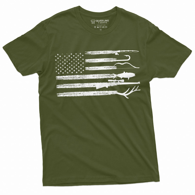 May include: A green t-shirt with a white distressed American flag design featuring fishing and hunting gear. The text "Silver Lake T-Shirts" is on the tag.