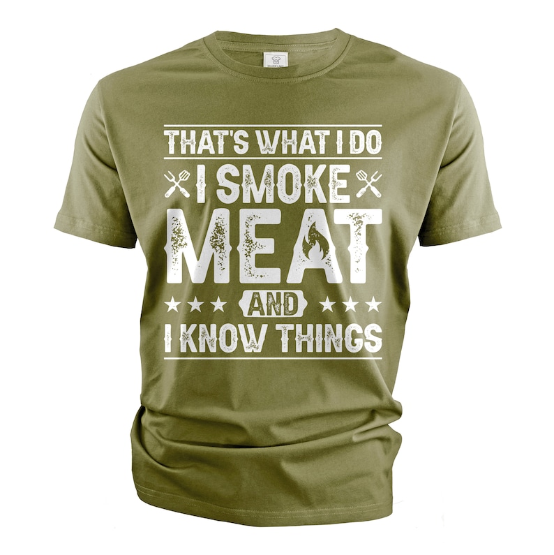 May include: A green t-shirt with a white graphic that says "That's what I do I smoke meat and I know things". The graphic also includes two crossed grilling forks and a flame.