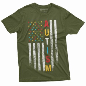Peut inclure: T-shirt vert olive avec un motif de drapeau am&eacute;ricain vieilli. Les &eacute;toiles du drapeau sont remplac&eacute;es par des pi&egrave;ces de puzzle color&eacute;es, et le mot "AUTISME" est imprim&eacute; verticalement en lettres grasses. Le t-shirt est de Silver Lake T-Shirts.