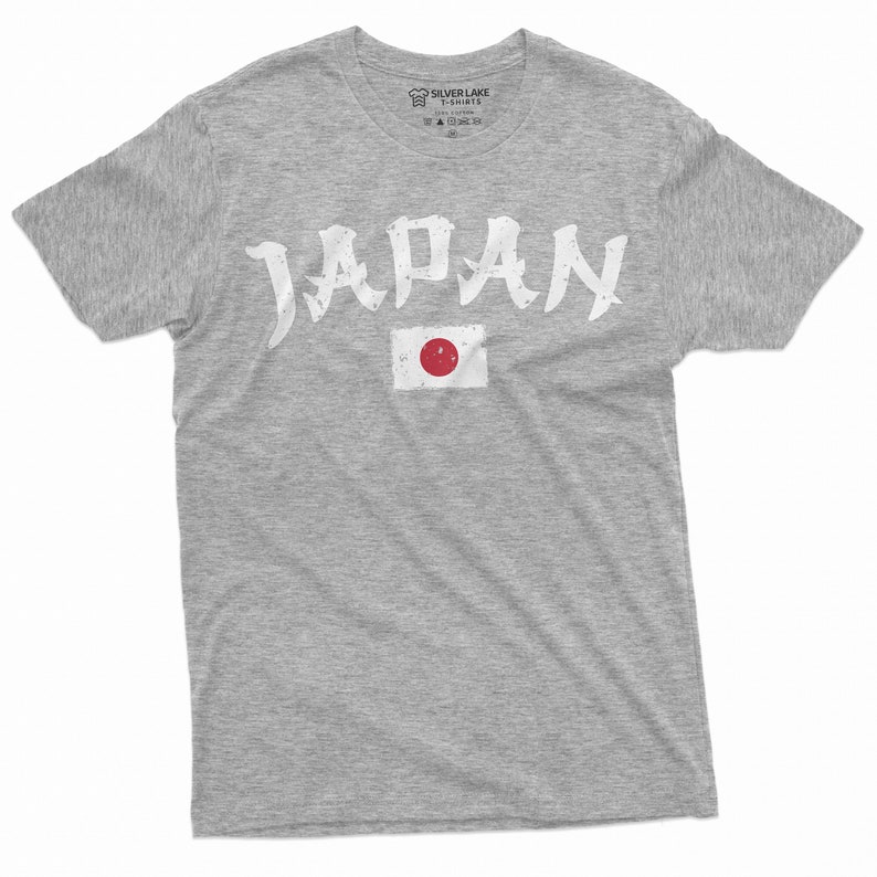 May include: A gray t-shirt with the word "JAPAN" printed in white with a stylized font. The Japanese flag is printed below the word.