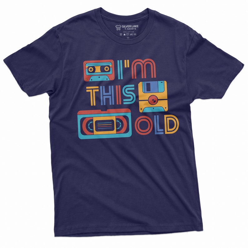 May include: A navy blue t-shirt with a retro design featuring a cassette tape, floppy disk, and VHS tape. The text "I'm This Old" is printed on the shirt.