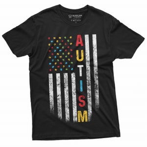 Peut inclure: T-shirt noir avec un motif de drapeau am&eacute;ricain vieilli. Les &eacute;toiles du drapeau sont des pi&egrave;ces de puzzle color&eacute;es, et le mot "AUTISM" est imprim&eacute; verticalement en plusieurs couleurs. Le t-shirt est de Silver Lake T-shirts.