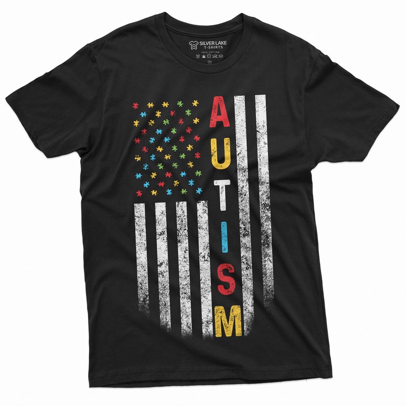 Peut inclure: T-shirt noir avec un motif de drapeau am&eacute;ricain vieilli. Les &eacute;toiles du drapeau sont des pi&egrave;ces de puzzle color&eacute;es, et le mot "AUTISM" est imprim&eacute; verticalement en plusieurs couleurs. Le t-shirt est de Silver Lake T-shirts.