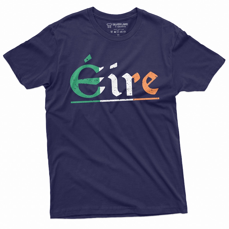 May include: A navy blue t-shirt with the word "&Eacute;ire" printed in white with green and orange accents. The word is stylized with a distressed look and is centered on the shirt. The Irish flag colors are incorporated into the design.