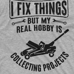 May include: A gray t-shirt with a black graphic that says "I fix things but my real hobby is collecting projects". The graphic includes two wrenches and a silhouette of a car jack.