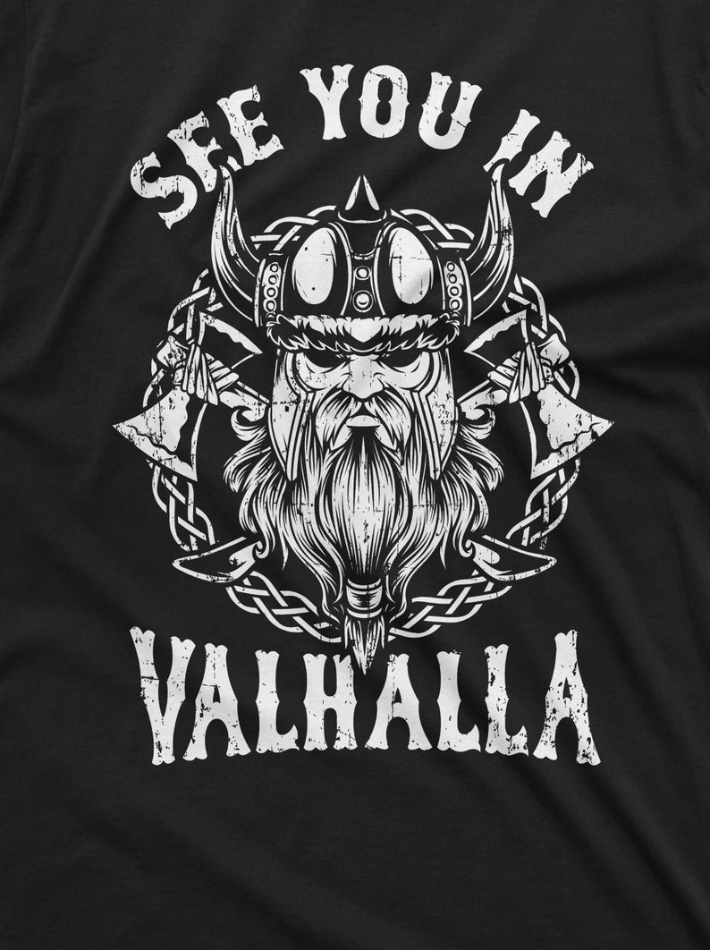 May include: Black t-shirt featuring a white graphic of a Viking with a horned helmet, long beard, and crossed axes. The text "SEE YOU IN VALHALLA" is arched above and below the Viking illustration.