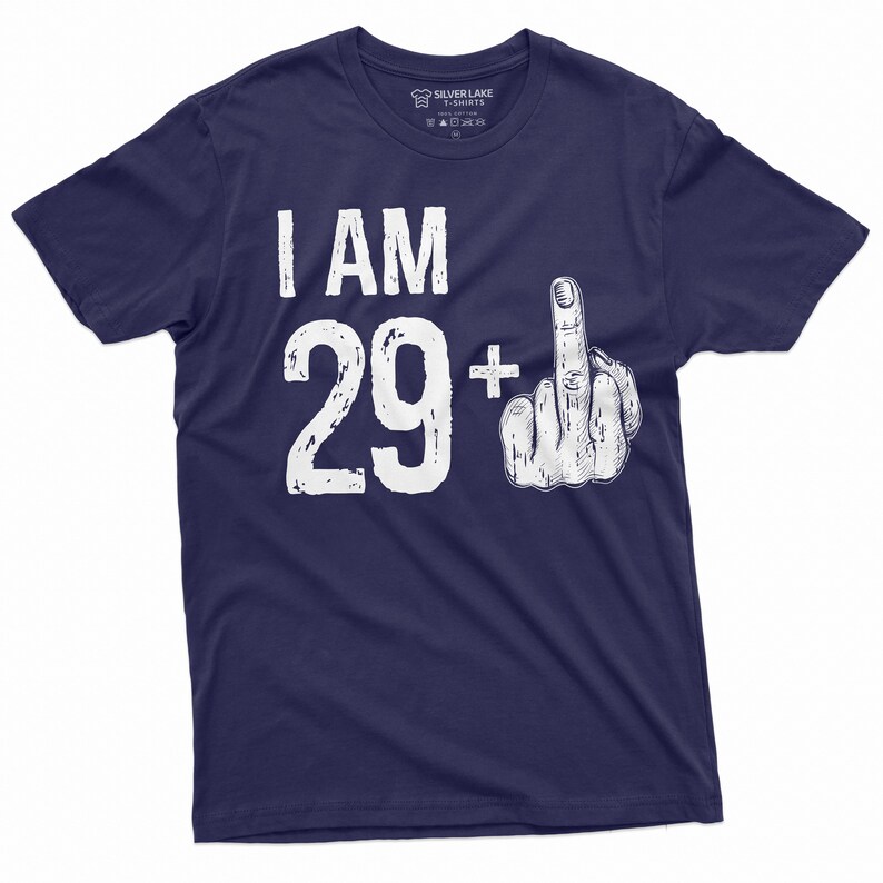 May include: Navy blue t-shirt with white text that reads "I AM 29+ " with a white middle finger graphic.