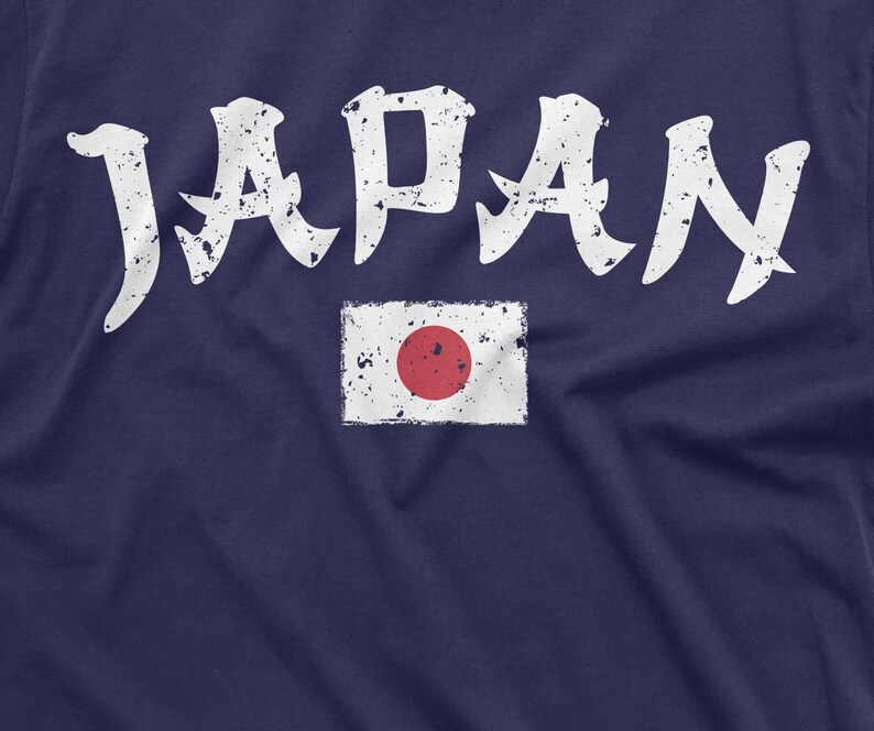 May include: A navy blue t-shirt with a white distressed graphic of the word "JAPAN" and a white distressed image of the Japanese flag with a red circle in the center.