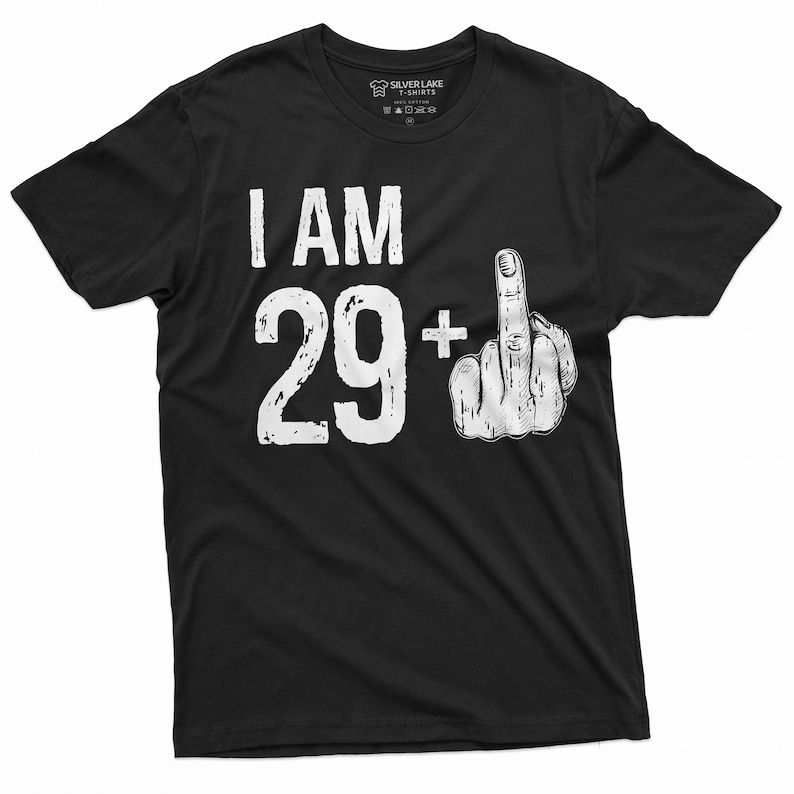 May include: Black t-shirt with white text that reads "I AM 29+ " with a white middle finger emoji next to the number.