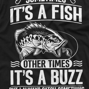 Pu&ograve; includere: T-shirt grafica in bianco e nero con un'illustrazione di un pesce e il testo "Sometimes it's a fish, other times it's a buzz, but I always catch something."