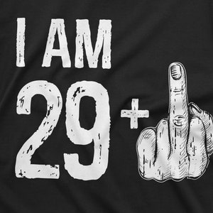 May include: Black t-shirt with white text that reads "I AM 29+" and a white illustration of a middle finger.