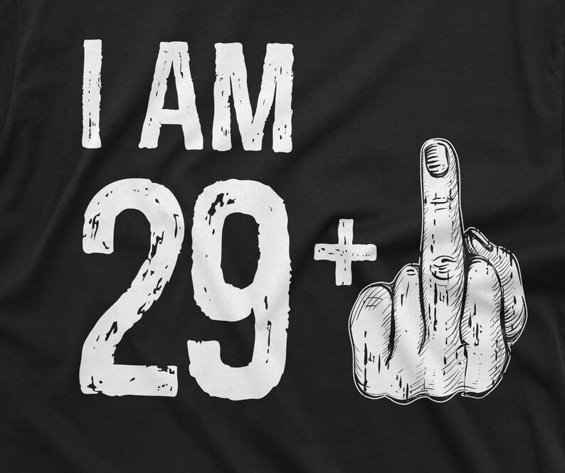 May include: Black t-shirt with white text that reads "I AM 29+" and a white illustration of a middle finger.