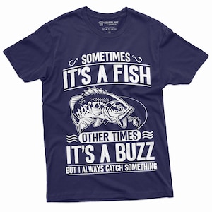 Pu&ograve; includere: Una t-shirt blu navy con una grafica bianca di un pesce e il testo "Sometimes it's a fish, other times it's a buzz, but I always catch something."
