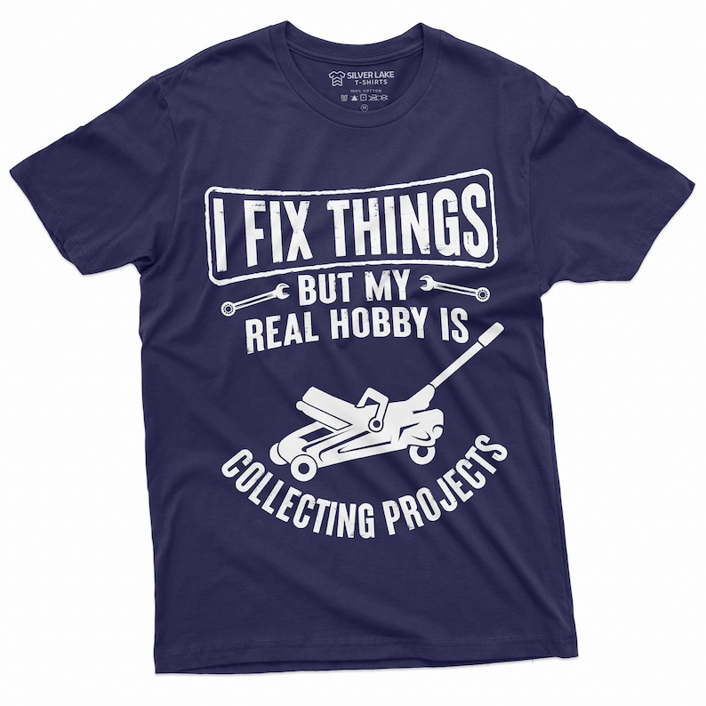 May include: A navy blue t-shirt with white text that reads "I fix things but my real hobby is collecting projects". The text is surrounded by wrench symbols. A white silhouette of a car jack is below the text.