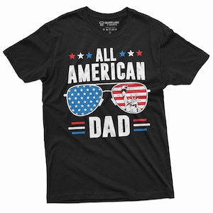 May include: Black t-shirt with a white graphic of sunglasses with an American flag design. The text "All American Dad" is printed on the shirt.