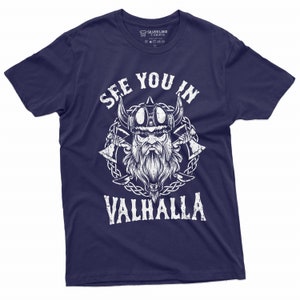 May include: Navy blue t-shirt with a white graphic of a Viking warrior and the text "SEE YOU IN VALHALLA". The design includes a Viking helmet, axes, and a beard. The shirt is from Silver Lake T-Shirts.