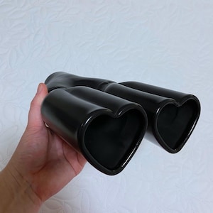 May include: A pair of black ceramic heart-shaped exhaust tips for a car.