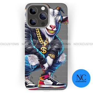 May include: A phone case with a cartoon goat wearing a gold chain and a black jacket. The goat is wearing a pair of blue jeans and a pair of red and white sneakers. The phone case is white with a clear back.