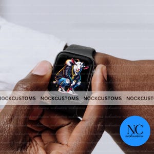 May include: A black smartwatch with a white goat wearing a gold chain and a blue and black jacket on the screen. The text "NOCKCUSTOMS" is visible on the bottom of the screen. The watch is being held by a person's hand.