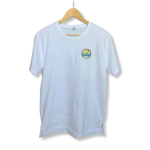 May include: White t-shirt with a small, round, colorful graphic of a sun, waves, and mountains.
