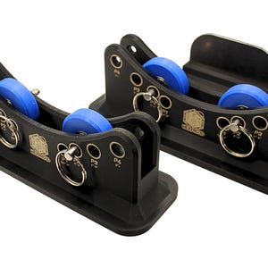 以下が含まれることがあります： 青いローラーと銀色のリングが付いた、2つの黒いブラケット型のデバイス。各デバイスは長方形のベースと穴の開いた湾曲した上部を備えています。デバイスには「P3」と「P4」の文字が印刷されています。