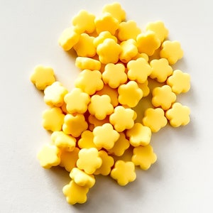 K&ouml;nnte beinhalten: Ein Haufen gelber, blumenf&ouml;rmiger Silikonperlen. Diese Perlen eignen sich perfekt f&uuml;r die Herstellung von Schmuck oder anderen Bastelarbeiten.
