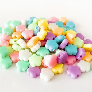 K&ouml;nnte beinhalten: Ein gro&szlig;er Haufen pastellfarbener, plastikfarbener Bl&uuml;tenperlen. Die Perlen sind in den Farben Rosa, Blau, Gr&uuml;n, Gelb und Lila.