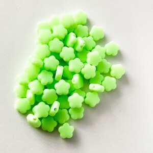 K&ouml;nnte beinhalten: Ein gro&szlig;er Haufen leuchtend gr&uuml;ner, blumenf&ouml;rmiger Silikonperlen.