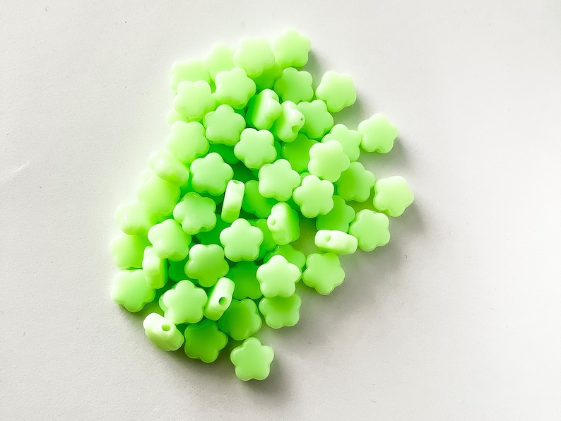 K&ouml;nnte beinhalten: Ein gro&szlig;er Haufen leuchtend gr&uuml;ner, blumenf&ouml;rmiger Silikonperlen.