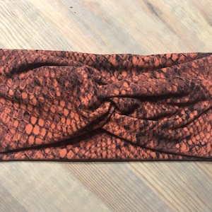 Peut inclure: Un bandeau de tête à motif brun et noir avec un nœud torsadé.
