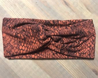 Puede incluir: Una diadema de color marrón y negro con un diseño de nudo retorcido.