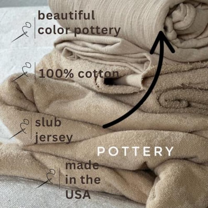 May include: A stack of beige cotton fabric with the words "beautiful color pottery", "100% cotton", "slub jersey", "POTTERY", "made in the USA" printed on it.