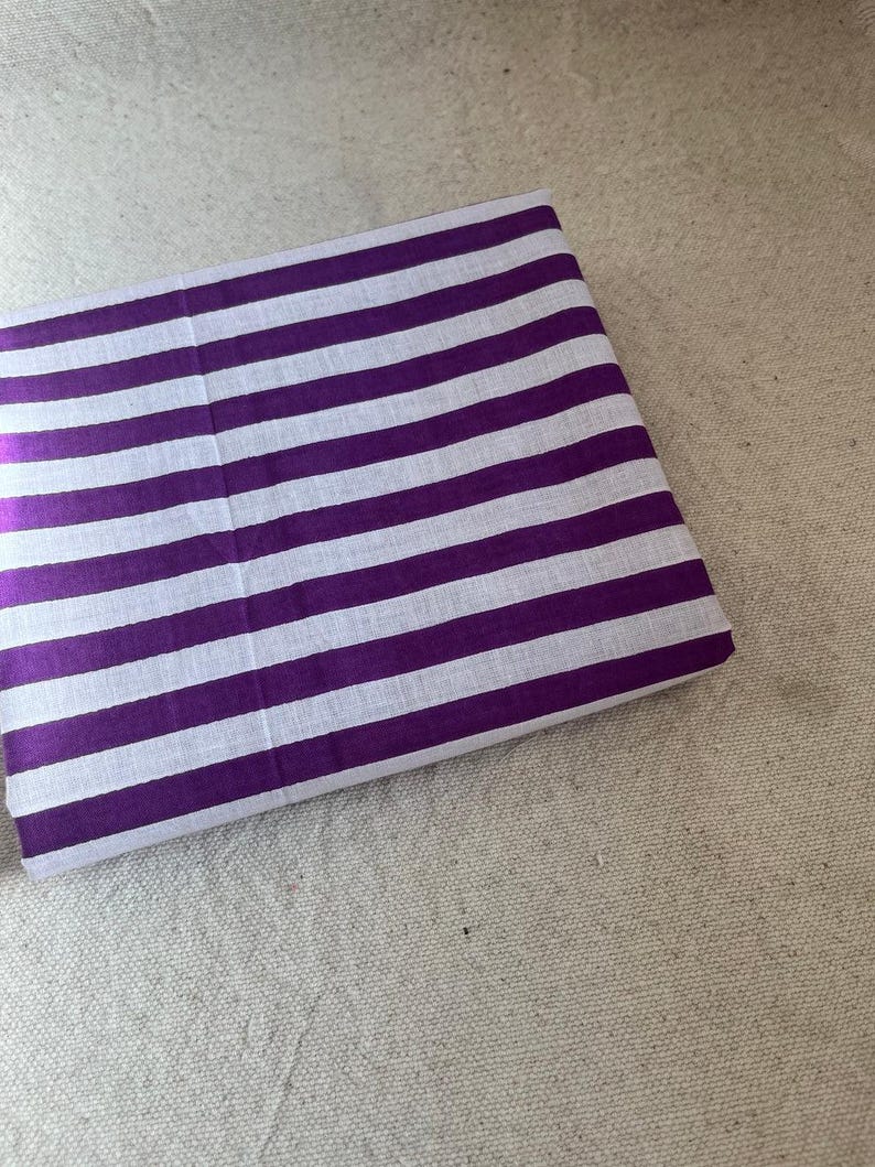 "Stacked Carnival Cotton fabric, showcasing its smooth, breathable texture and soft drape. Perfect for sewing t-shirts, dresses, and lounge sets. The natural cotton fibers provide a comfortable feel, making it a great choice for everyday wear and sustainable fashion."