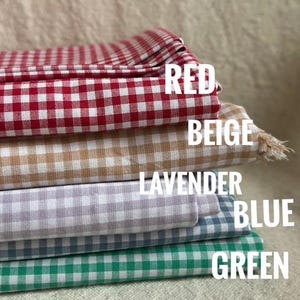 May include: Stack of five gingham fabric swatches in red, beige, lavender, blue, and green.
