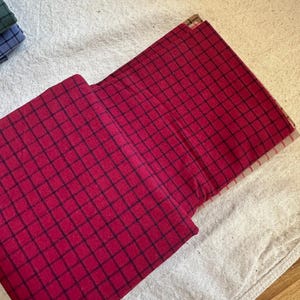 Brushed cotton grid plaid fabric draped on a sewing table, with scissors and thread nearby. The fabric’s clean lines and soft feel suggest its readiness for quilting or garment-making. Woven design adds depth while the brushed cotton enhances comfort. A dream material for home sewers, designers, and textile lovers seeking quality.