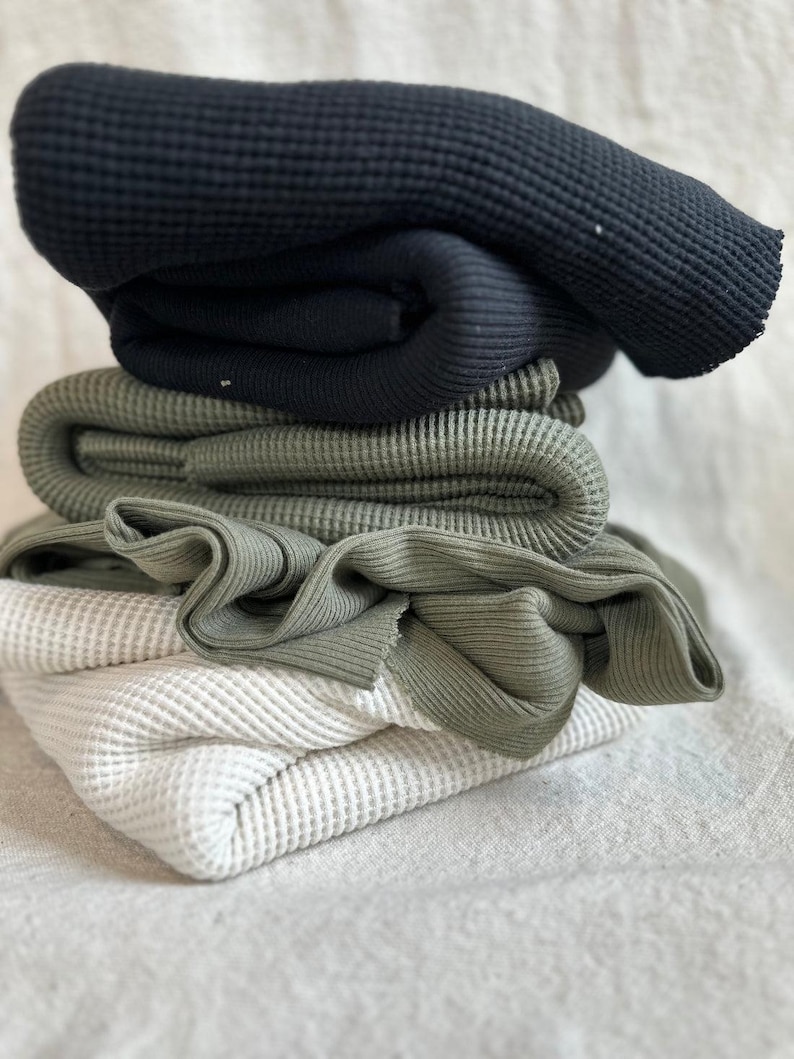 Premium heavy cotton waffle knit fabric shown with a thick textured surface and classic waffle pattern. This high-quality cotton knit fabric is soft, breathable, and substantial, making it ideal for sewing hoodies, sweaters, joggers, loungewear, baby clothing, and cozy blankets. The waffle texture adds dimension and warmth while maintaining flexibility and comfort. Fabric is sold by the half yard and is suitable for both apparel sewing and home projects.